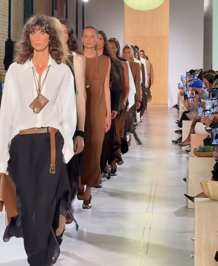 Models walking the runway showcasing sheer outfits and toned abs at New York Fashion Week event.