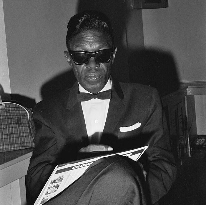 Man in sunglasses and tuxedo reading a magazine, reflecting on concerts fans wish they had skipped.