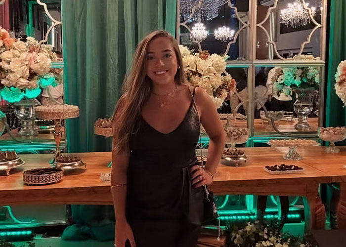 Young woman in a black dress standing in front of a decorated table, related to plastic surgeon and butt lift procedure news.