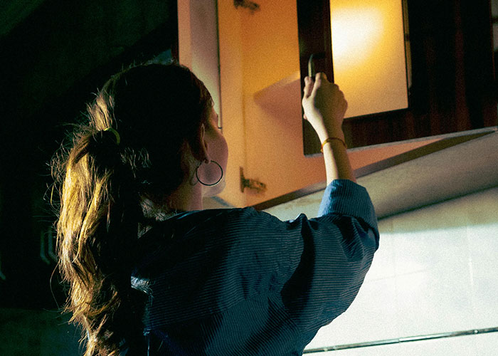 Woman with ponytail opening cabinet door in dim light, representing creepy things women do that cross the line.
