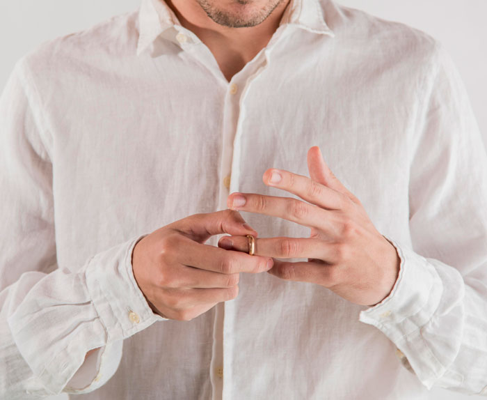 Man in white shirt removing ring from finger, representing professors who left an impression with hilarious student reviews.