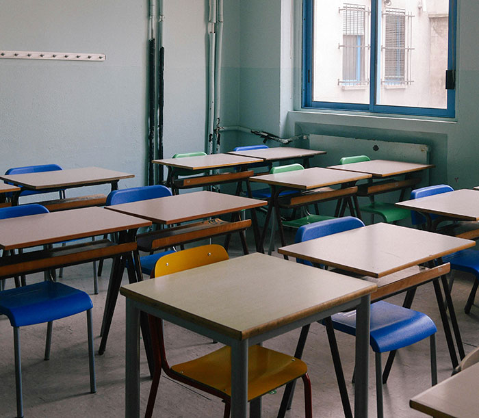 Empty classroom with desks and chairs in a school setting related to teacher arrested for using poop spray and causing damage.