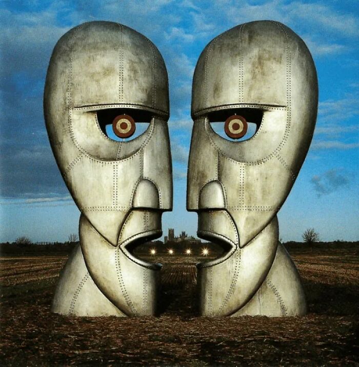 Metallic sculpture of two large human faces facing each other in a field, symbolizing unexplained internet mysteries.