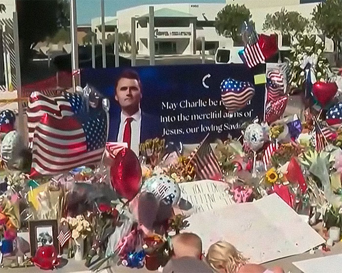Memorial site with flowers, balloons, and flags honoring Charlie Kirk, related to sisters who destroyed the memorial and faced homelessness.