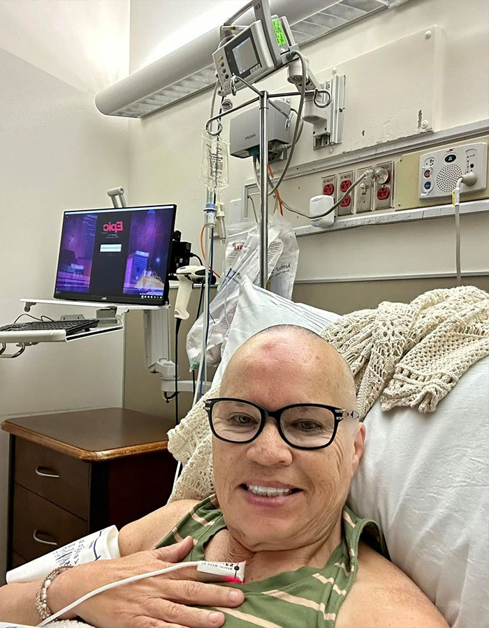 Woman in hospital bed receiving treatment, smiling, after symptoms were misunderstood before cancer diagnosis.