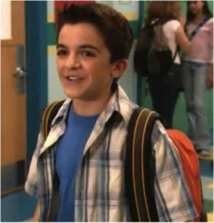 Young Nickelodeon actor smiling in school hallway with backpack, featured in fundraiser for homeless and street-side makeover.
