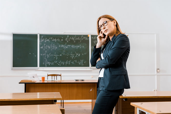 Woman in a classroom looking upset while on phone call about school contacting mom instead of husband. Woman in a classroom looking upset while on phone call about school contacting mom instead of husband.
