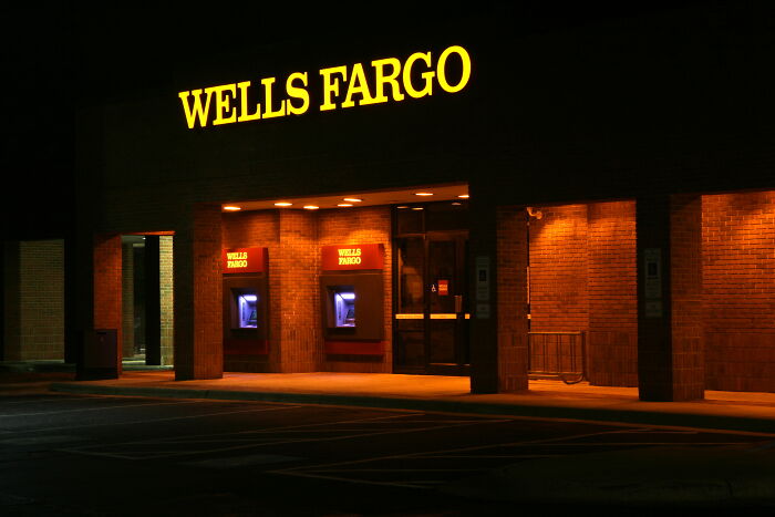Wells Fargo bank exterior at night with illuminated signs representing famous fraud cases and financial scandals.