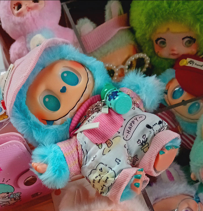 Colorful quirky dolls with large blue eyes surrounded by plush toys representing modern AI inclusion trends.