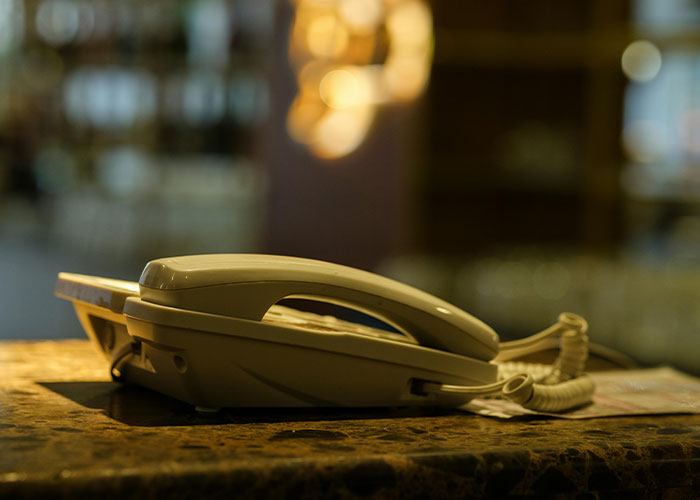 Beige landline telephone on a marble counter with blurred warm lights in the background showing coincidence concept.