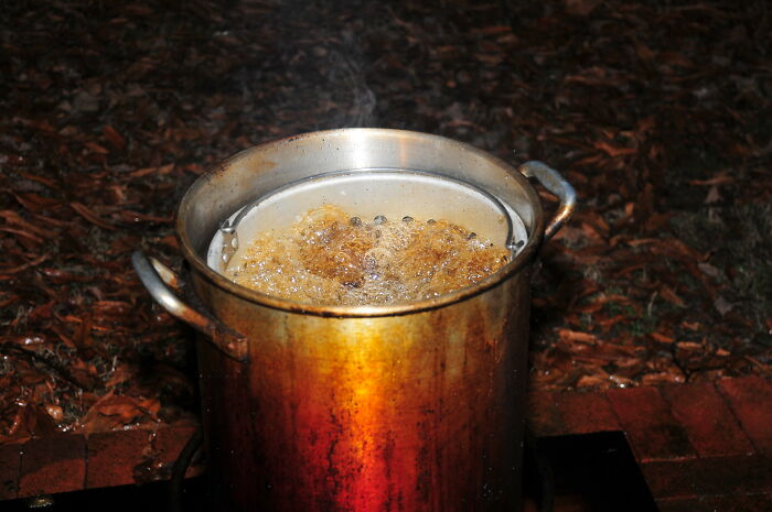 Large metal pot with boiling oil outdoors, illustrating unholy health violations in restaurants kitchens during inspections.