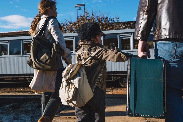A family at a train station with backpacks and luggage, illustrating shocking family secrets revealed by people online.