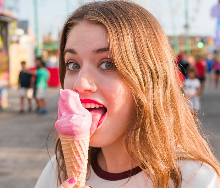 Young woman enjoying a pink ice cream cone outdoors, illustrating unique women dealbreakers that confuse men in relationships