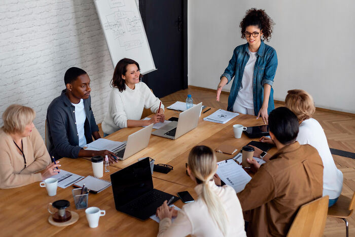 A diverse group in a meeting room discussing real-life stories of people becoming what they once hated.