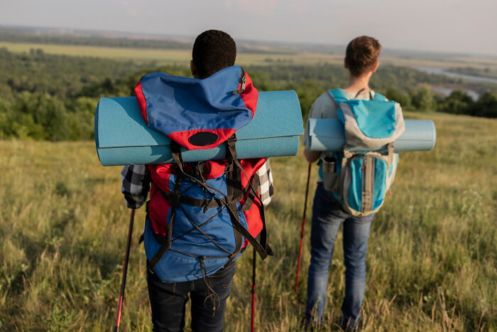 Two hikers carrying backpacks and mats, enjoying a scenic view, inspired by life-changing sentences concept.