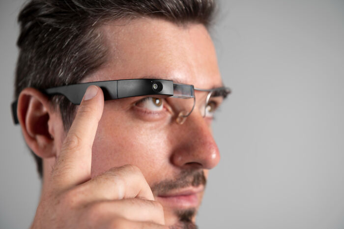 Man wearing smart glasses, interacting with the device, illustrating technology as the next big thing that totally flopped.