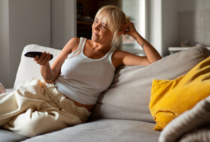 Woman looking heartbroken on a couch while parents prefer watching TV all day rather than spending time with her
