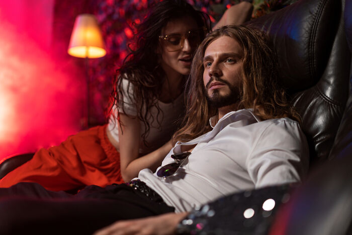 Couple sharing a secret moment on a leather couch, illustrating hidden stories found while surfing online.