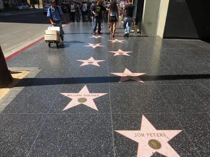 Hollywood Walk of Fame stars with people walking, highlighting popular travel destinations that differ from pictures.