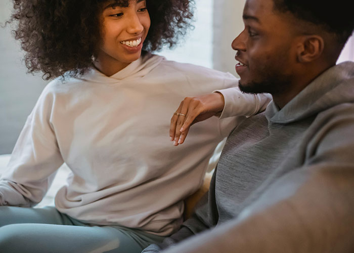 Young woman smiling and leaning toward a man who looks uncomfortable in a casual indoor setting about creepy behavior.