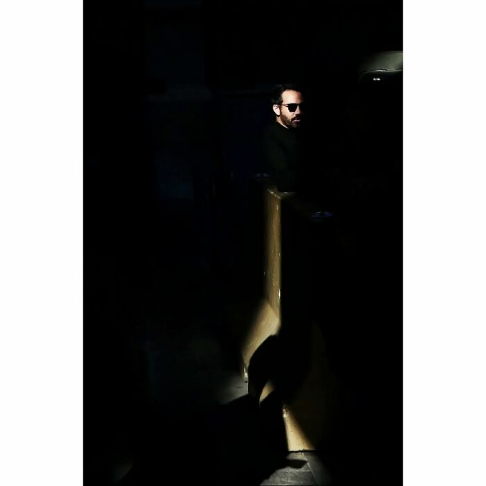 Man in dark clothing and sunglasses standing in a dimly lit street photo full of funny coincidences.