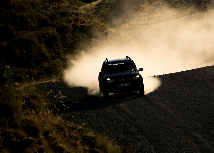 SUV driving on a dusty gravel road in a hilly area, illustrating one of the incredible coincidences in nature.