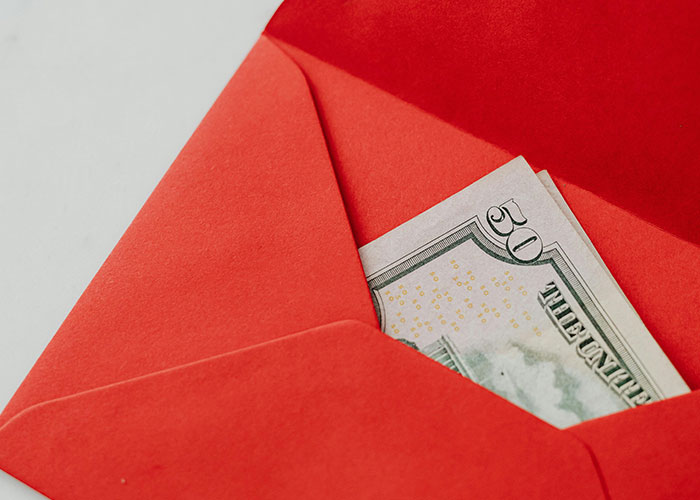 Red envelope partially open revealing a fifty dollar bill representing hidden gems discovered after moving into new homes.