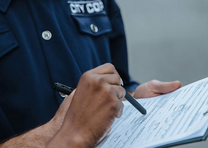 Police officer in navy uniform holding a pen and writing notes on a form, related to terrifying true stories.