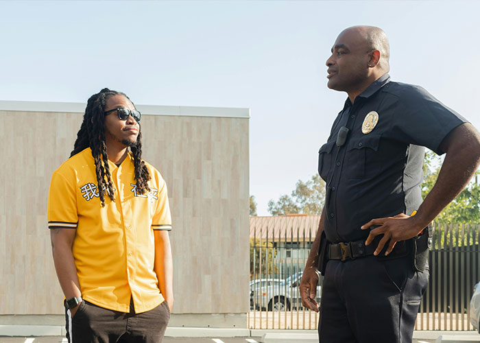 Man in yellow shirt and sunglasses talking to police officer outside, illustrating criminal fails in a casual encounter.