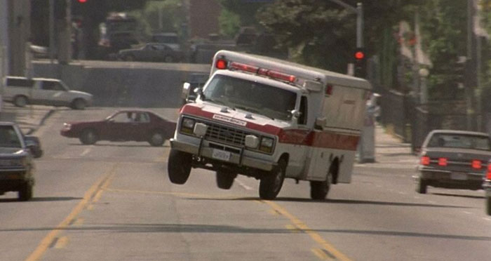 Ambulance driving quickly with front wheels lifted off the road, showcasing EMT and paramedic emergency response action.