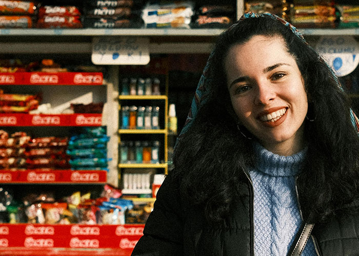 Young woman with dark curly hair smiling in a store setting, illustrating incredible coincidences that sound fake but are true.