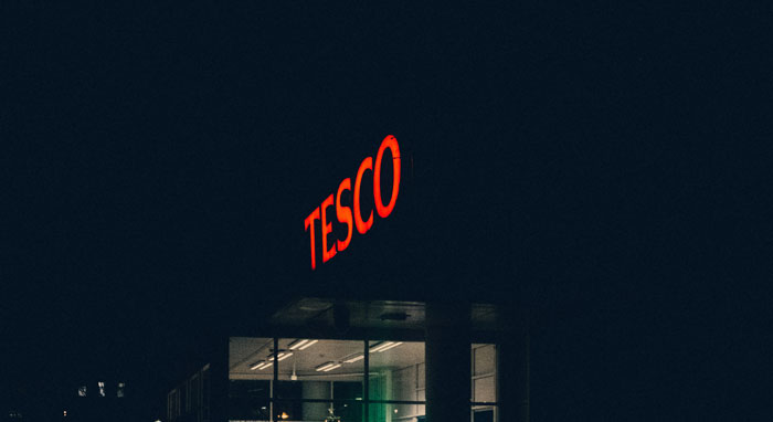 Tesco store exterior at night with illuminated red sign, highlighting a popular retail location linked to clever loopholes.
