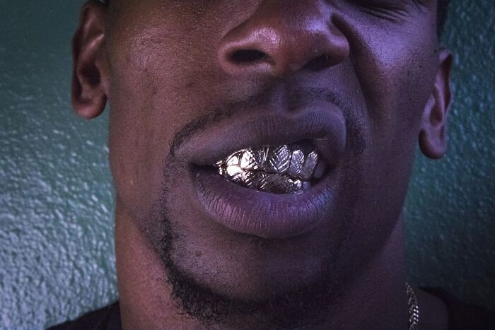 Close-up of a man with a silver grill on his teeth, symbolizing chaotic stories shared by food delivery drivers.
