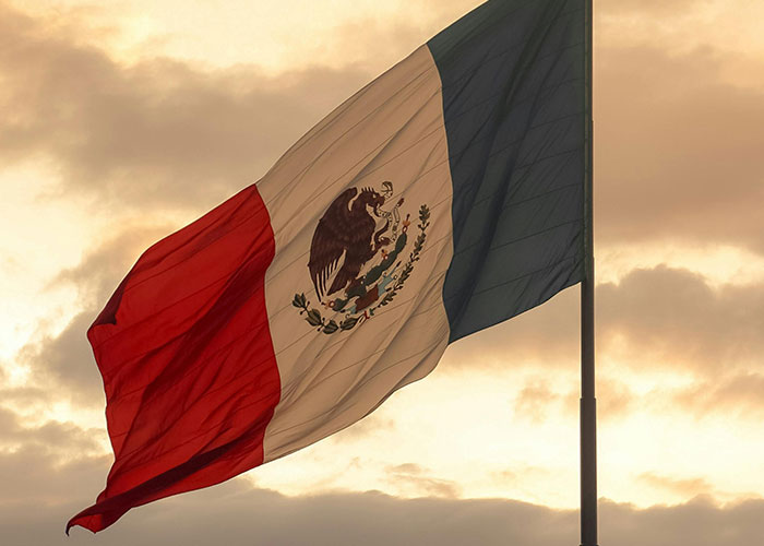 Mexican flag waving against a cloudy sky, symbolizing the setting for terrifying true stories that are hard to believe.