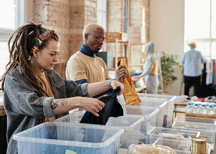 Two people sorting clothes in a thrift store, illustrating common purchases people have ditched due to high price tags.