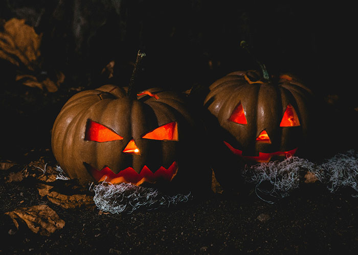 Two glowing jack-o'-lanterns with menacing faces in a dark setting, evoking terrifying true stories.