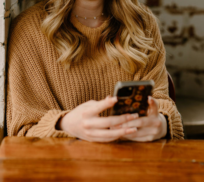 Mujer usando teléfono móvil con funda floral, mostrando cómo los teléfonos ayudan a descubrir verdades ocultas.