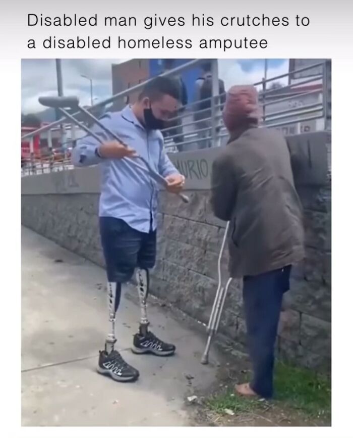 Disabled man with prosthetic legs hands crutches to a homeless amputee, showcasing a wholesome act of kindness and support.