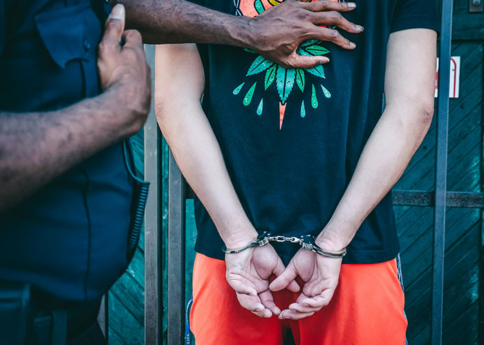 Person in handcuffs being held by police officer, illustrating criminal fails in a real-life law enforcement scenario.