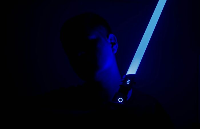 Silhouetted person holding a glowing blue light saber illustrating chaotic stories from food delivery drivers.