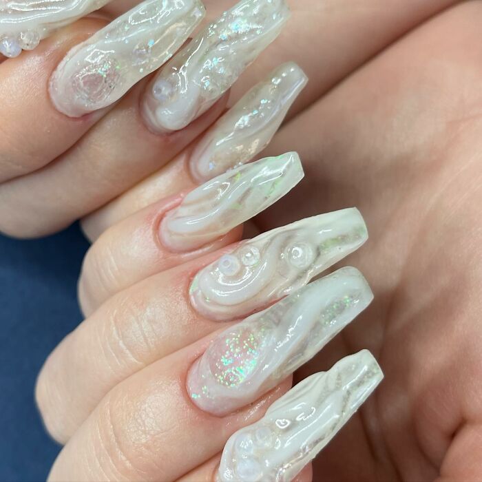Close-up of unique iridescent nail designs with textured 3D details showcasing innovative and rule-breaking nail art styles.