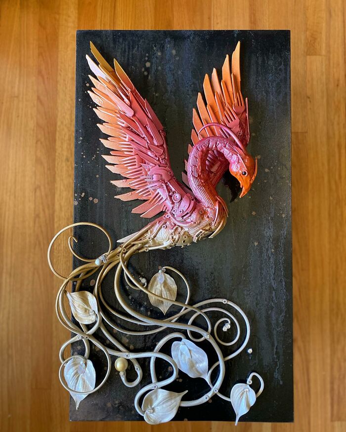 Intricate animal sculpture made from recycled trash, featuring a colorful bird with mechanical wings and curling metal vines.