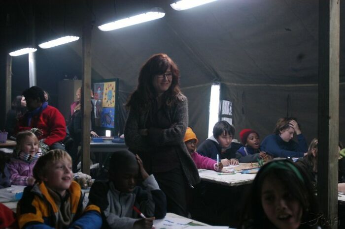 Woman surrounded by children in a classroom setting, representing well-written female characters in movies breaking stereotypes.