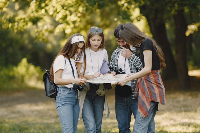 Group of young people outdoors looking worried while checking map, illustrating woman worried creepy Airbnb host texts concept.