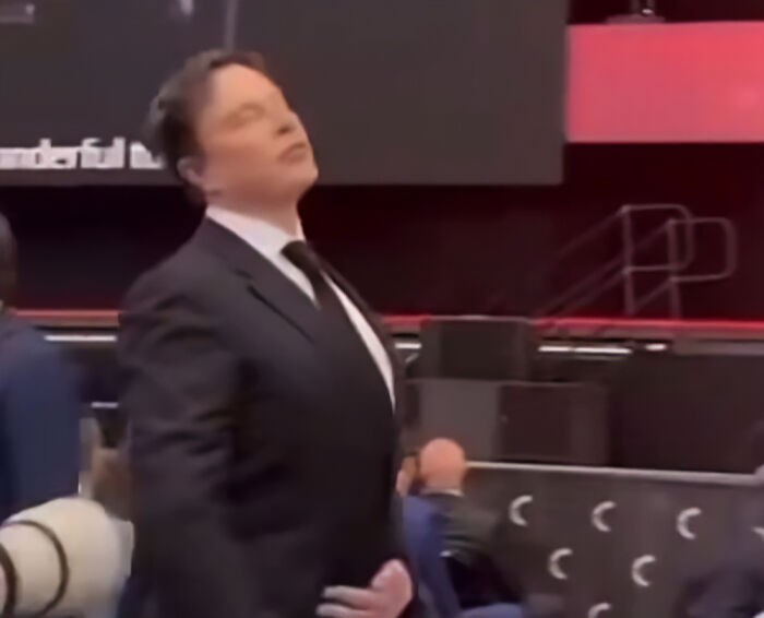 Elon Musk in a black suit at a public event, sparking wild conspiracy theories after a strange funeral appearance.