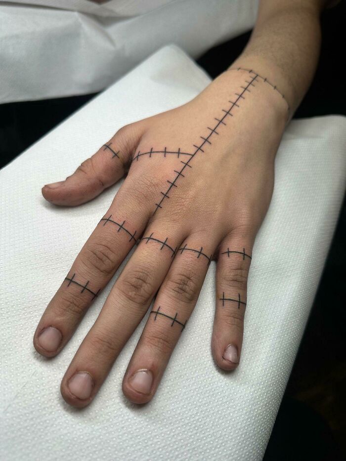 Hand tattoo design featuring stitched line patterns across fingers and back, showcasing challenges faced by tattoo artists with clients.