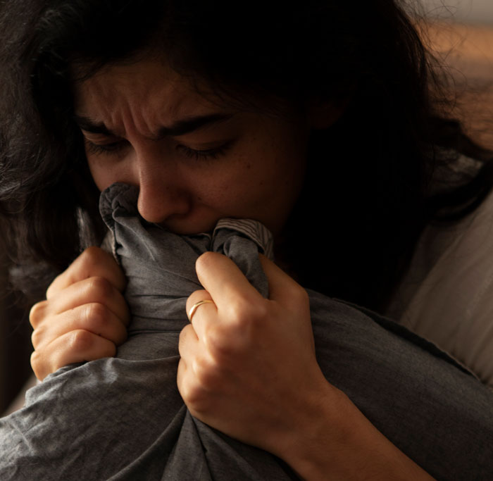 Woman devastated and emotional, holding fabric close to face, reflecting on model boyfriend being out of her league