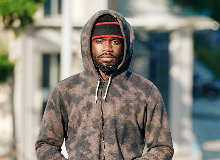 Man in a hoodie and beanie walking outdoors, representing themes of single mom abandoning toddler and parents restarting life.