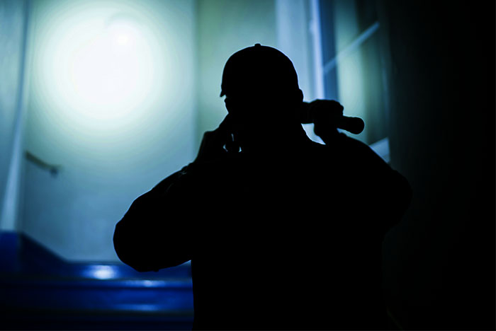 Silhouetted police officer holding a flashlight in a dark hallway, symbolizing cops sharing horrible witnessed events.