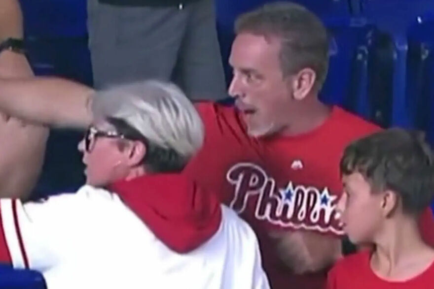 Woman mistaken for Phillies Karen wearing glasses and white hoodie during home run ball meltdown at baseball game.